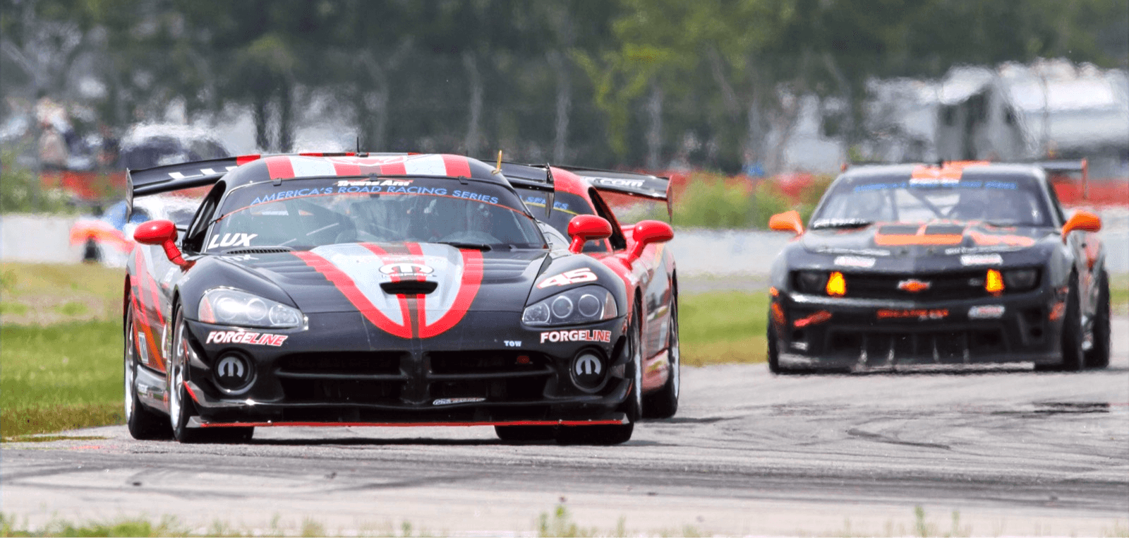 Two GT race cars battling through a corner on the road course at Brainerd International Raceway, Minnesota
