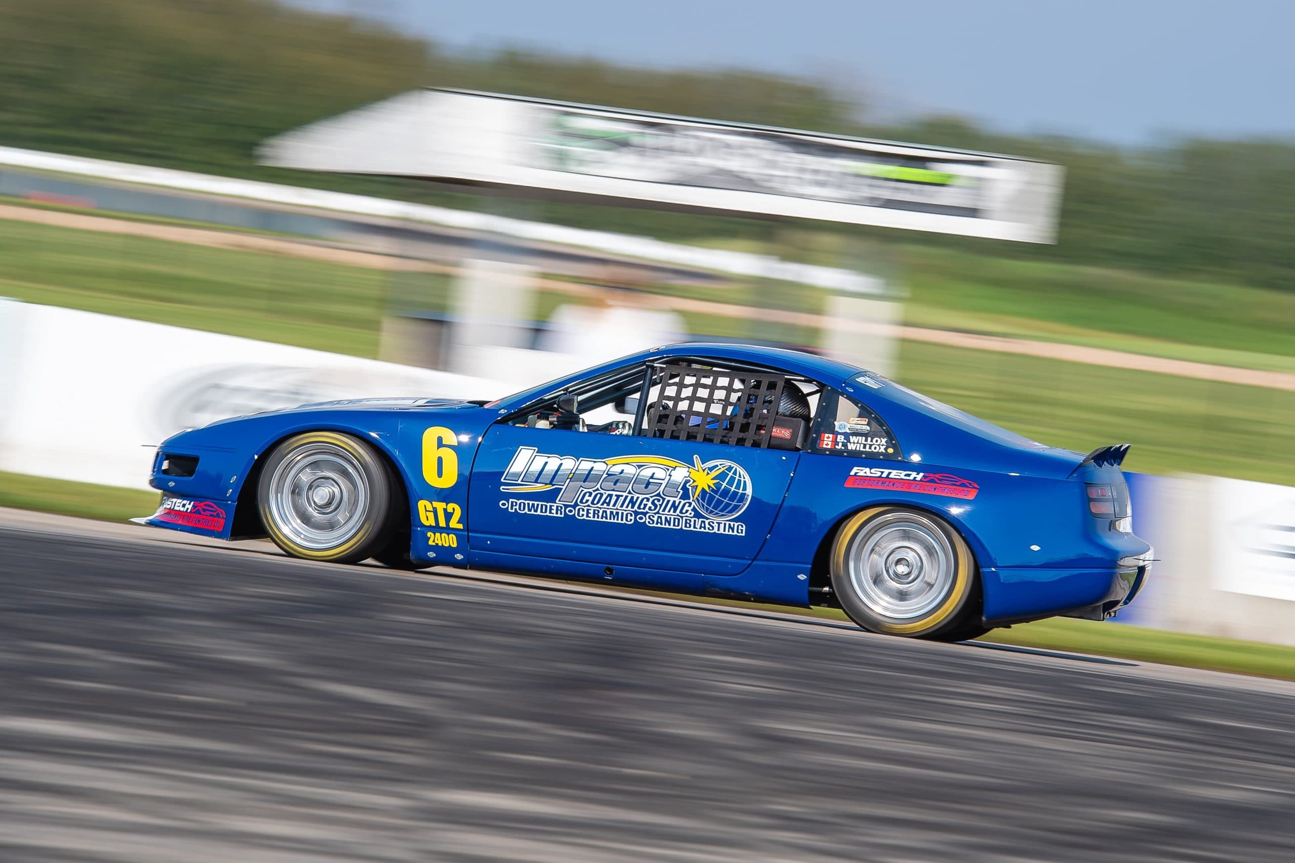 A blue GT2 sedan leans into a corner on the road course at RAD Torque Raceway