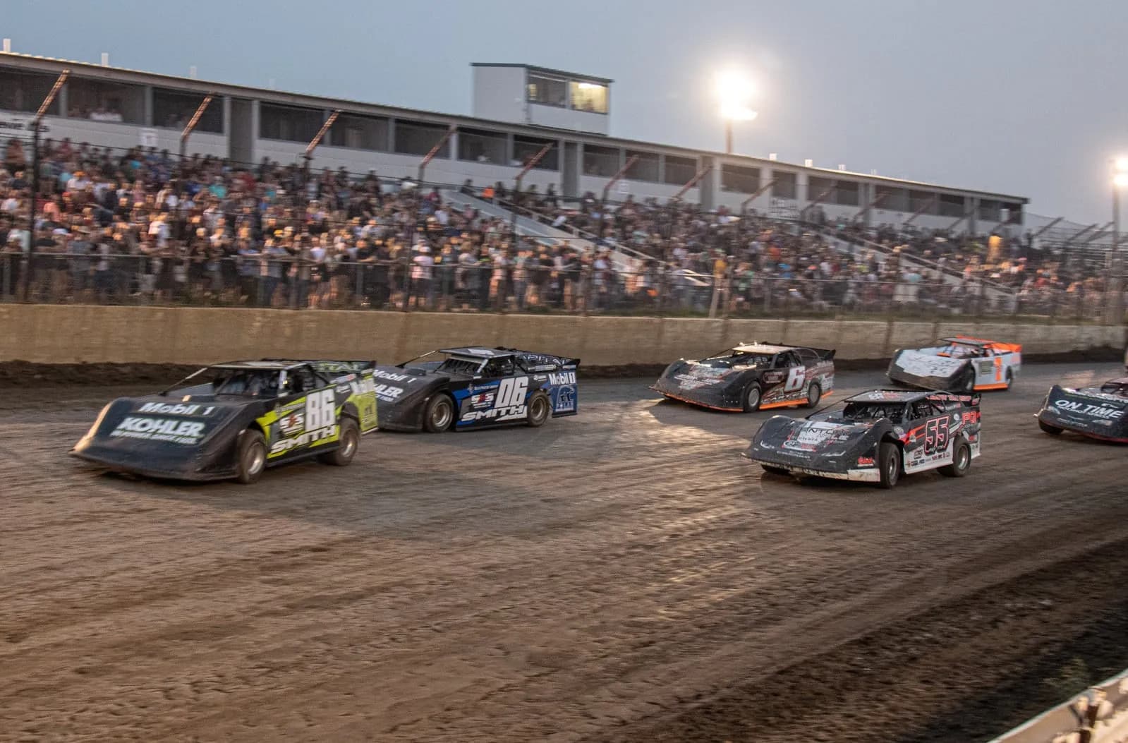 Late model dirt cars race three-wide before a packed grandstand at RAD Torque Raceway, Edmonton