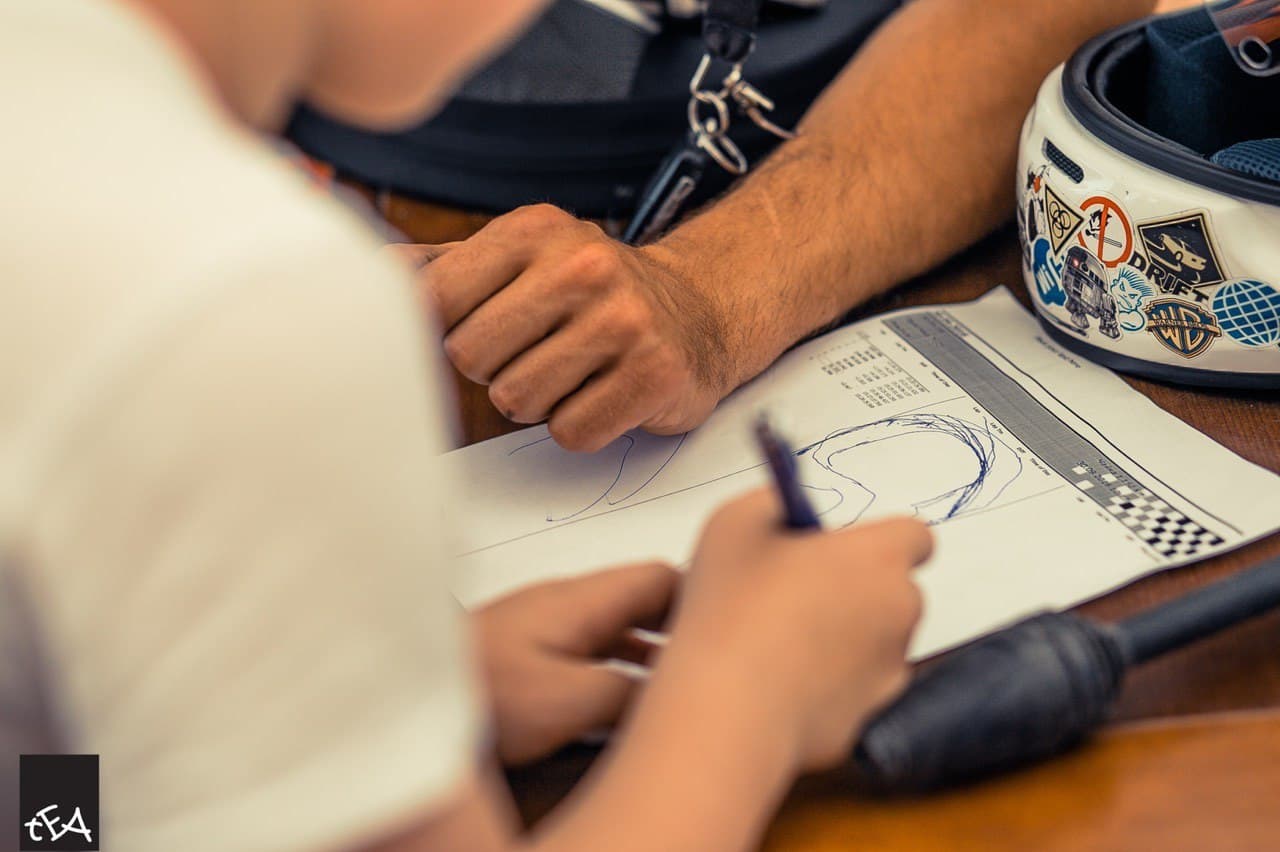 Coach reviews a hand-drawn track map with a young driver at Avtodrom Chaika