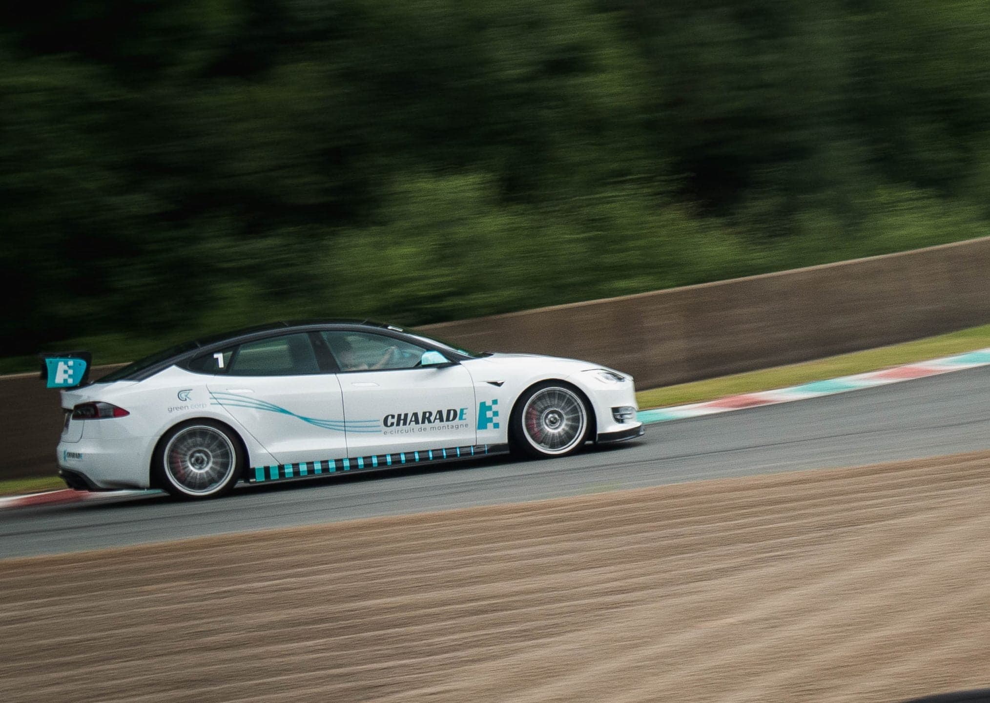A Tesla wearing Circuit de Charade e-circuit livery rounds a bend during the Electric Festival