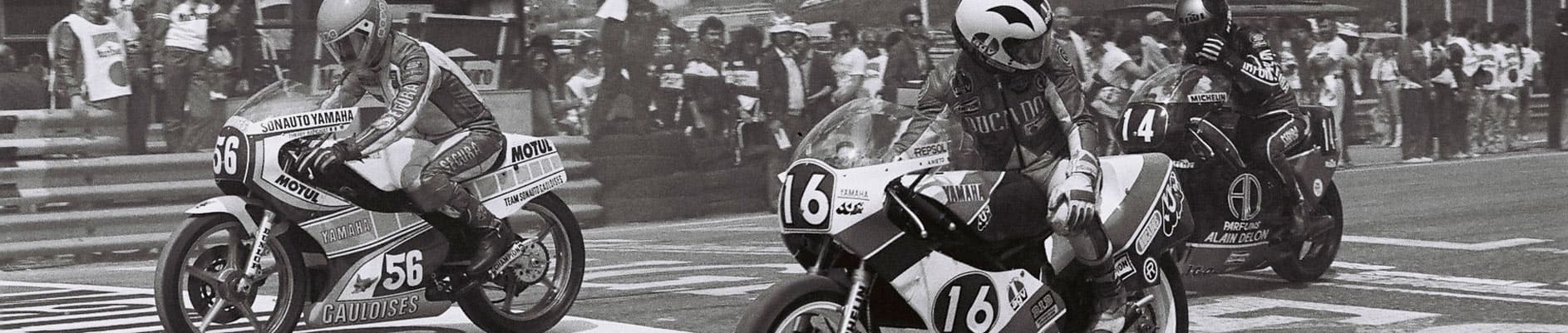 Black and white photo of three motorcycle racers on the grid at Circuito del Jarama, Madrid