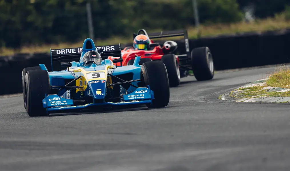 Blue and red single-seater formula cars exiting a corner at Mondello Park circuit