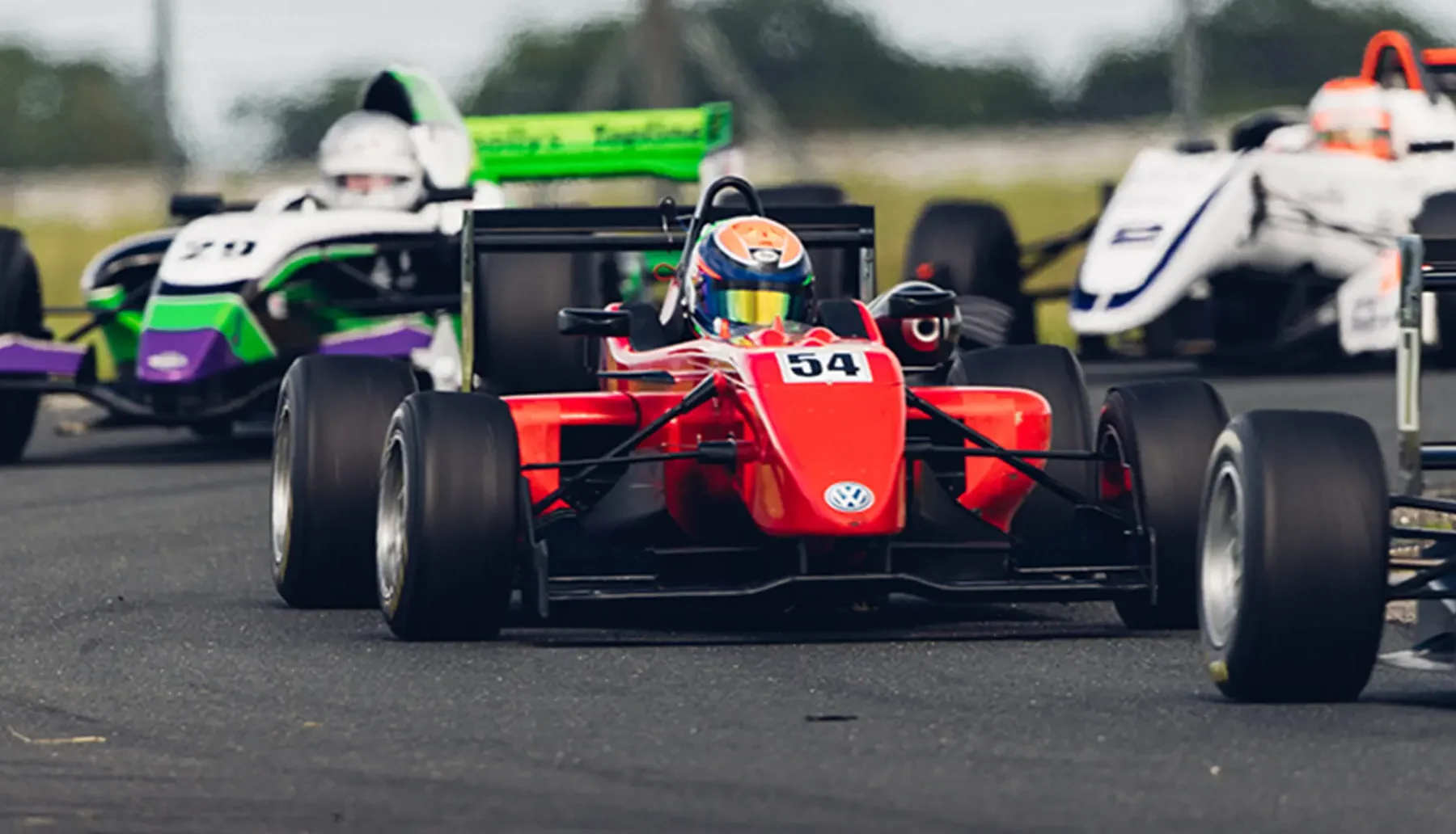 Pack of open-wheel formula cars racing side by side at Mondello Park, County Kildare