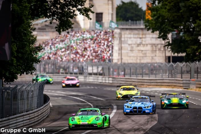 GT3 cars cornering tightly on the narrow street circuit with grandstand crowds behind at Norisring, Nuremberg