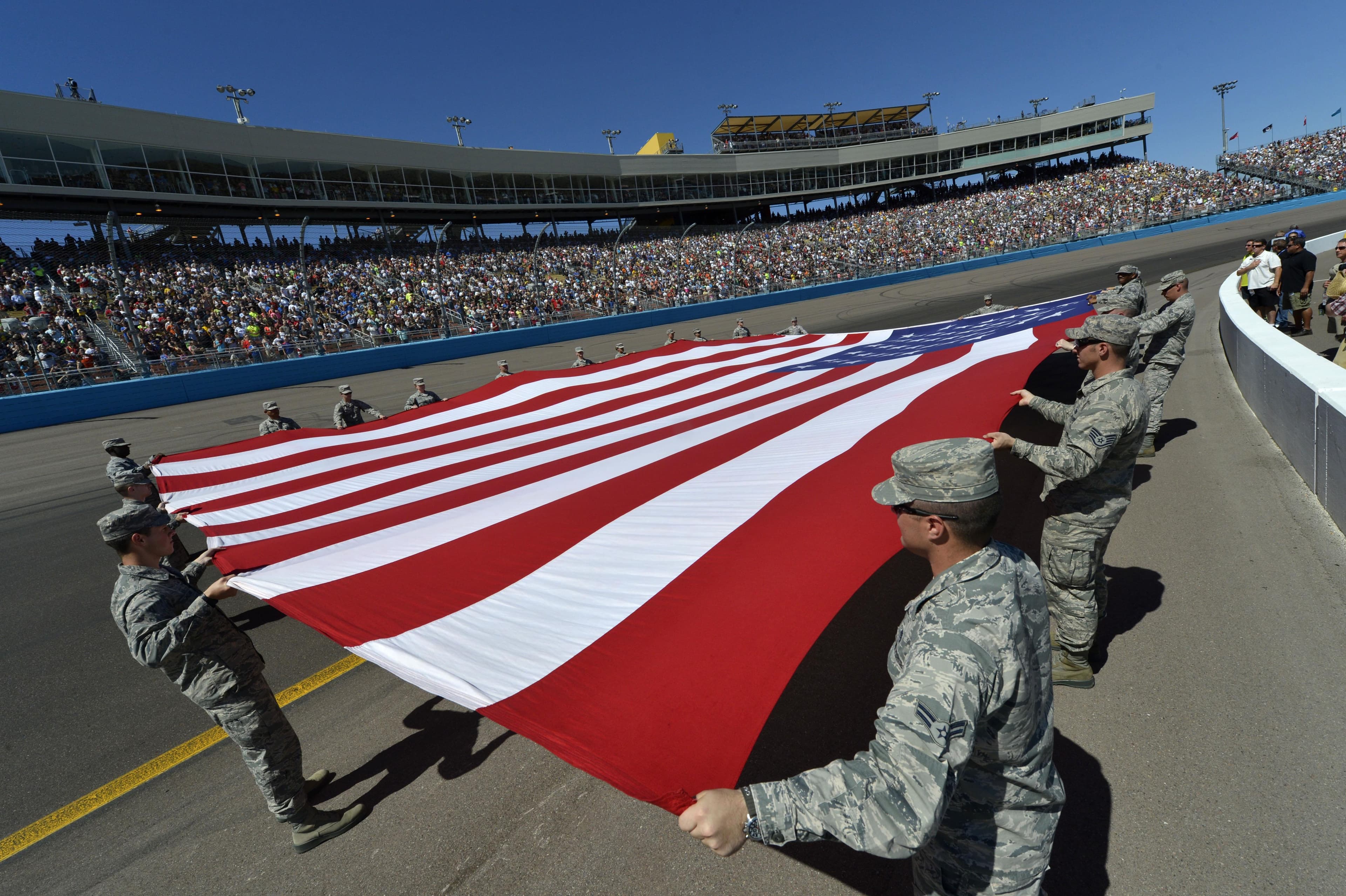 Air Force airmen carry a large American flag across the infield at Phoenix International Raceway prior to a NASCAR race, March 2015